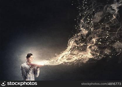 Blow dust from pages. Young man with opened book in hands blowing on pages