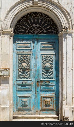 Blue aged Tunisian wooden door with arch and ornament. Culture and architecture of Tunisia
