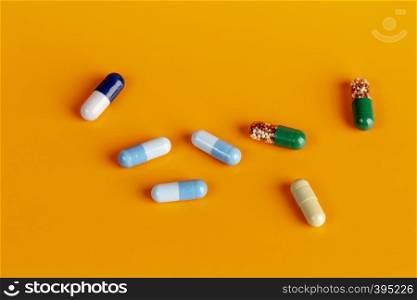 Blue and green medicine capsules on orange background. Blue and green medicine capsules
