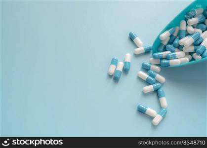 Blue and white capsules pill in plastic spoon and on blue background. Antibiotics drug resistance. Antimicrobial capsule pills. Pharmaceutical industry. Pharmacy drugstore products. Pharmaceutics.