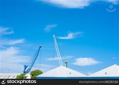 Blue and white cranes at a storage building in blue sky