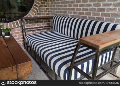 blue and white stripe fabric sofa and wood desk beside brick wall