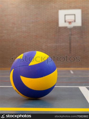 Blue and yellow ball on blue court at break time, school gym