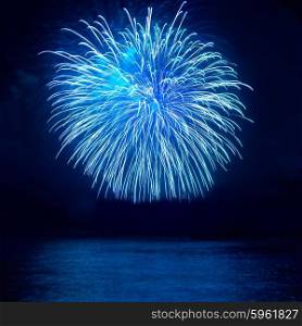Blue ball fireworks above lake with reflection on water with black sky background