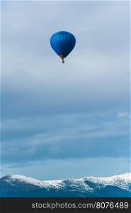 Blue balloon in the blue cloudy sky