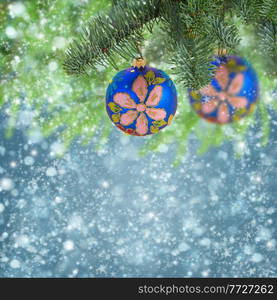 blue balls hanging on evergreen tree on  christmas  blue background with snow. christmas ball hanging on evergreen tree