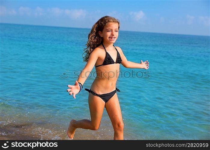 blue beach kid girl with bikini jumping and running splashing water