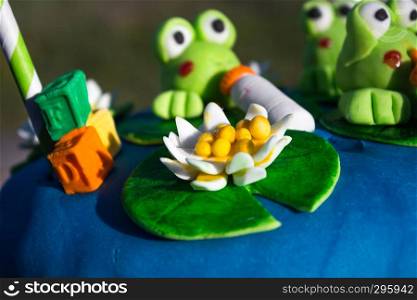 blue birthday cake with green frogs figures