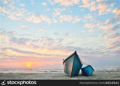 Blue boats on beach at sunrise