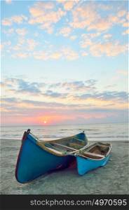 Blue boats on beach at sunrise