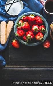 Blue bowl with fresh strawberries on dark wooden background, top view. Tiramisu preparation