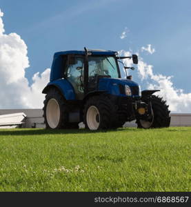 Blue Brilliant Agricultural Tractor on Green Declivity Field