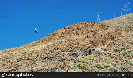 Blue cabin cable car with tourists climbing ropes stretched to the volcano Teide on Tenerife island.