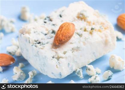 Blue cheese and almonds on a blue plate. Selective focus. Blue cheese and almonds on blue plate
