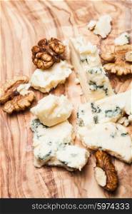 Blue cheese and walnuts close up on olive wooden board. Roquefort and walnuts