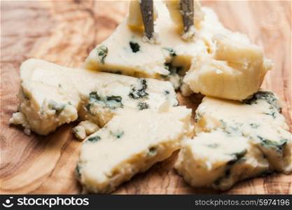 Blue cheese close up on olive wooden board. Roquefort and walnuts