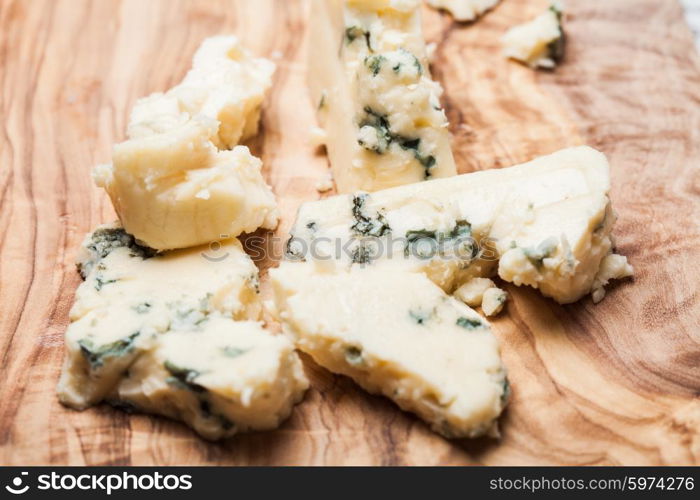 Blue cheese close up on olive wooden board. Roquefort and walnuts