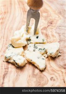 Blue cheese close up on olive wooden board. Roquefort and walnuts