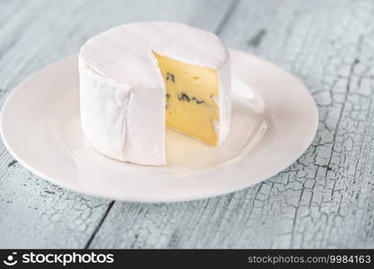 Blue cheese under a rind of white mould on the plate