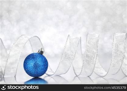 Blue Christmas ball and ribbon on abstract glitter silver background
