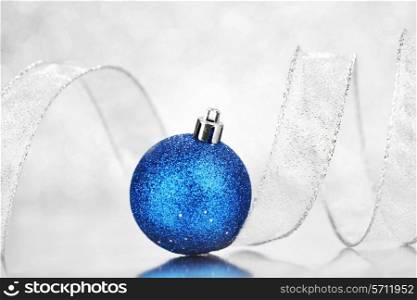 Blue Christmas ball and ribbon on abstract glitter silver background