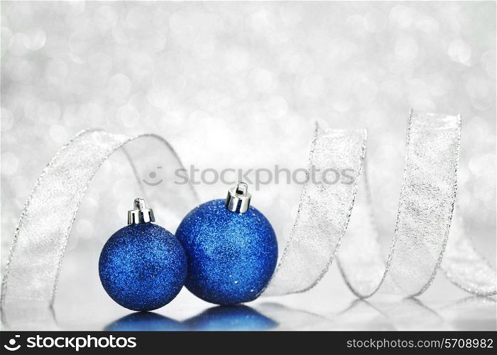 Blue Christmas balls and ribbon on abstract glitter silver background