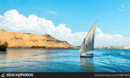 Blue cloudy sky over river Nile and sailboat in Aswan