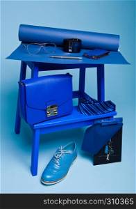 Blue color fashion style still life setup on blue background with shoe tie glasses bag pen and notebook