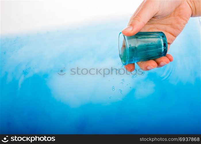 Blue color glass in hand over blue color water