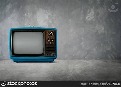 Blue color old vintage retro Television on cement table with background .