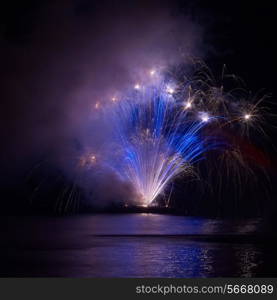 Blue colorful fireworks on the black sky background. Holiday celebration.