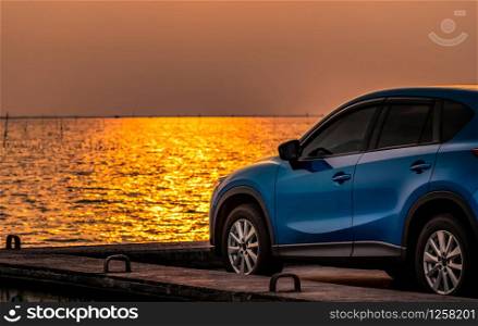 Blue compact SUV car with sport and modern design parked on concrete road by the sea at sunset. Environmentally friendly technology. Electric car technology and business. Hybrid auto and automotive.