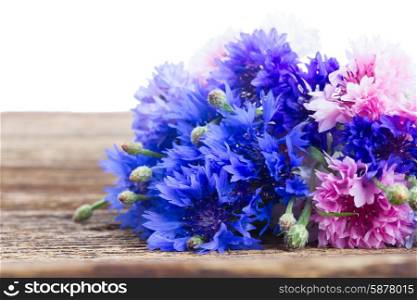 Blue cornflowers. Blue cornflowers on wooden table over white background