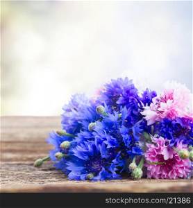Blue cornflowers on wooden table over gray background. Blue cornflowers