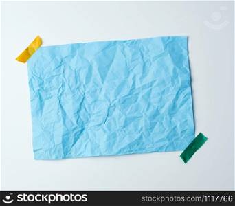 blue crumpled sheet of paper glued with adhesive tape on a white background, place for text