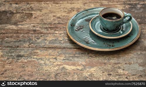 Blue cup of black coffee on wooden background. Vintage style still life