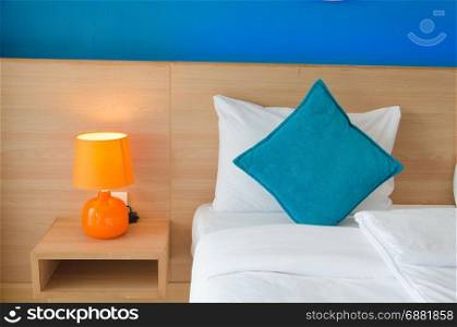 Blue cushions and orange lamps on the bed.