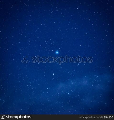 Blue dark night sky with big bright starin the centre. Space milkyway background