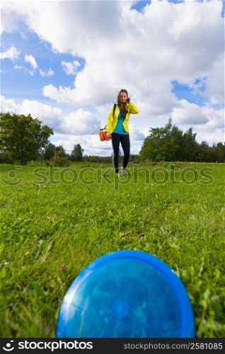Blue disc on the lawn, on background woman walks over disc