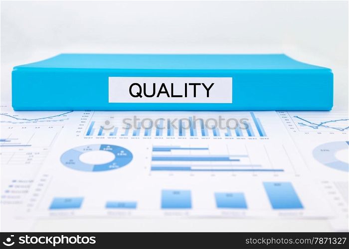 Blue document binder with quality word place on graphs, charts and business evaluation reports. concept for management plan