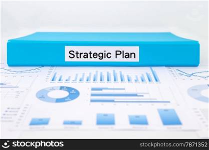 Blue document binder with strategic plan word place on graph analysis and evaluation report