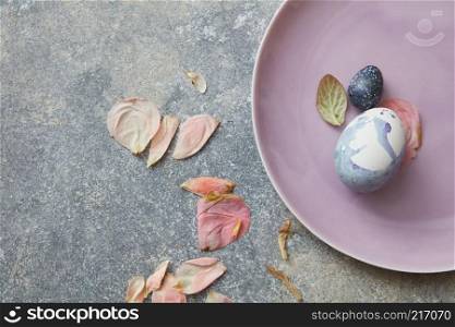 Blue easter eggs on plate with dried petals. eggs on pink plate