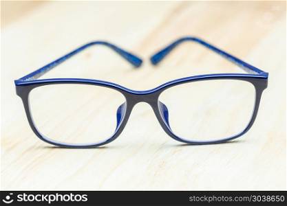 Blue eye glasses on wood table for business, education concept d. Blue eye glasses on wood table for business, education concept design.