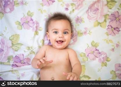 Blue-eyed baby lying on a flowery sheet