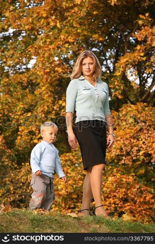 blue-eyed blond goes for a walk with the son in the park in autumn