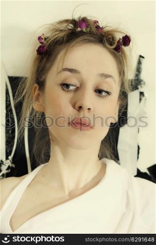 Blue-eyed face of a beautiful young woman with roses woven into the hair