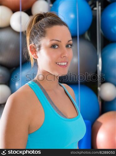 Blue eyes beautiful woman smiling at gym portrait with swiss and pilates yoga balls background