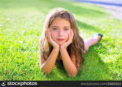 blue eyes children girl relaxed on the garden grass lying with hands in face