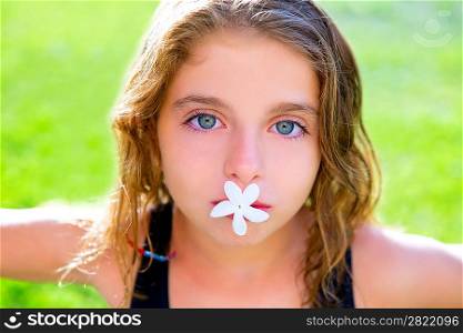 blue eyes children girl with jasmine flower in mouth at garden grass