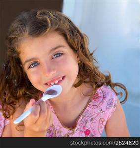 Blue eyes kid girl eating breakfast with spoon portrait